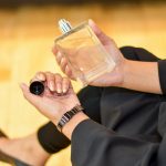 Close-up of a woman holding a Terre d'Hermes perfume bottle indoors, showcasing elegance and luxury.